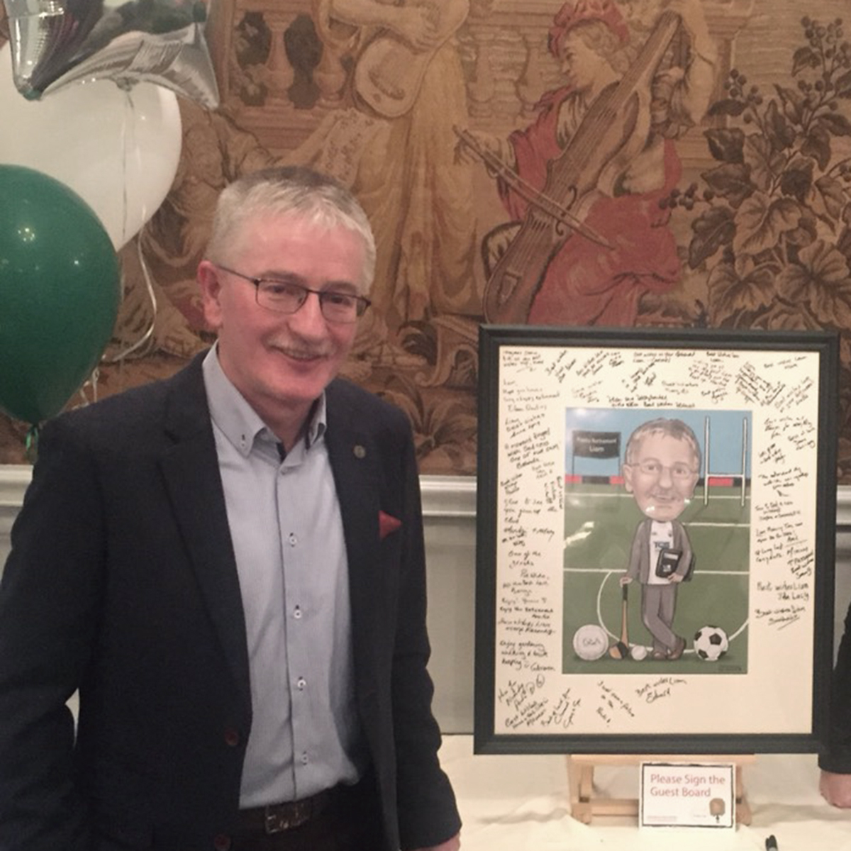 Liam standing beside his caricature gift at his retirement party.
