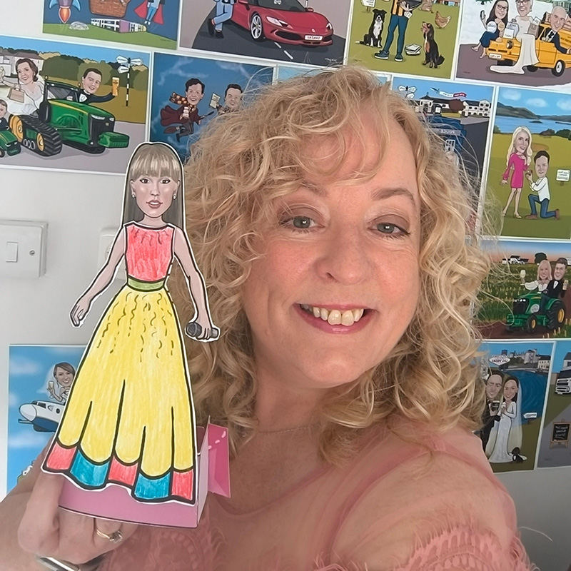 Carmel Grant posing with her popstar paper doll who is wearing a long princess style dress ready for a ball